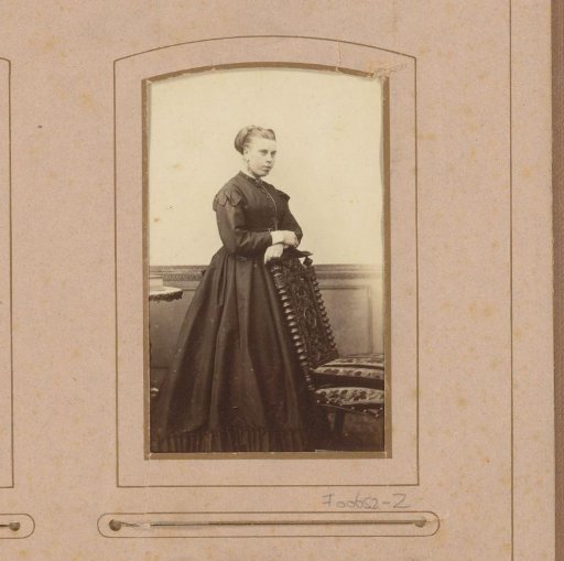 Portrait of a woman, standing by a chair