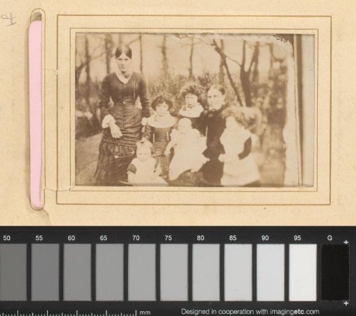 Group portrait of two women and five girls in the woods