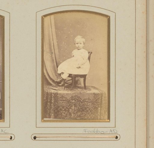 Portrait of a girl in a white dress on a chair on a table