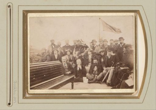 Group portrait of men and women on a boat, including a man with a bagpipe