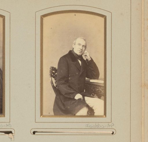Portrait of a man, seated at a table on which a book lies