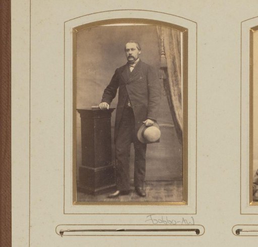 Portrait of a standing man with hat in hand, leaning on a column