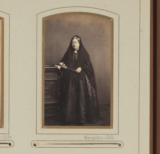 Portrait of a standing woman in black clothing with white lilies in her hand