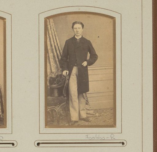 Portrait of a standing man by a chair with a hat