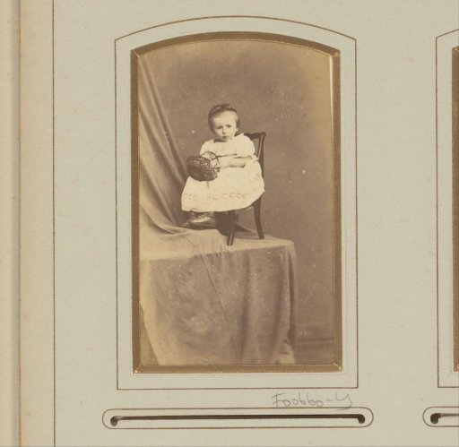 Portrait of a girl in a white dress with a basket on a chair on a table