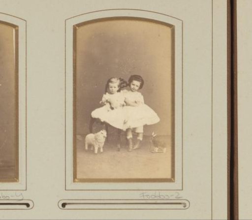 Portrait of two girls in white dresses on a chair with two toys