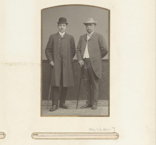 Portrait of two standing men with hat and walking stick