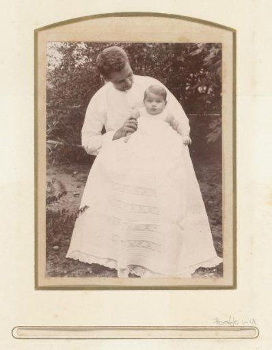 Portrait of a man with a baby in a christening gown on his lap