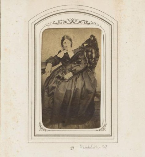 Portrait of a seated elderly woman with a white cap with ribbons