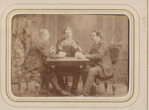 Group portrait of three men playing cards and reading