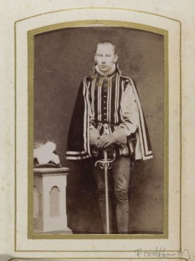 Portrait of a young man in costume next to a pedestal