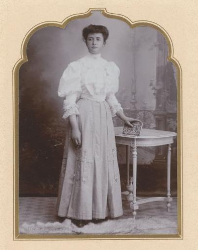 Portrait of a standing woman with a photo album in her hand beside a table
