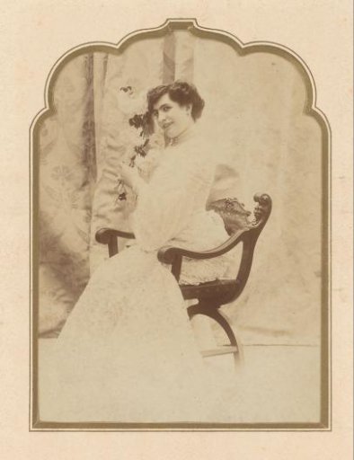 Portrait of a seated woman in a white lace dress with flowers
