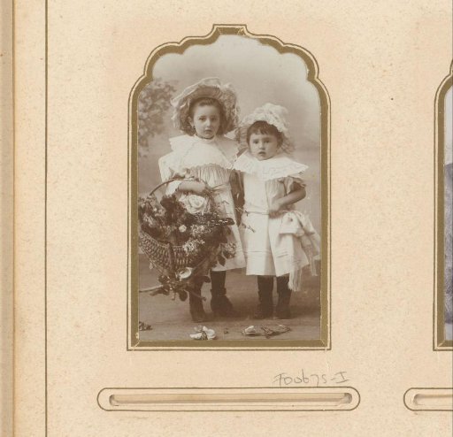 Portrait of two girls in white dresses and hats with a basket full of flowers