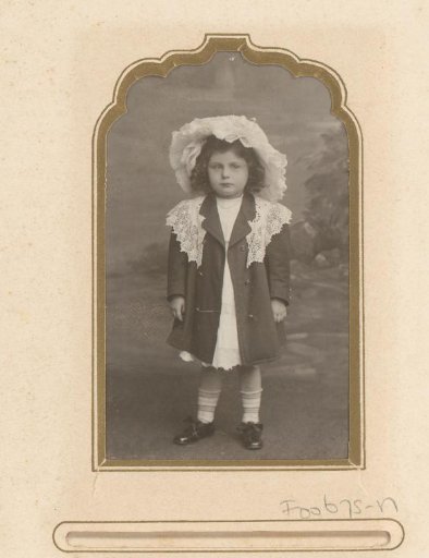 Portrait of a girl in a jacket with a white lace collar and hat
