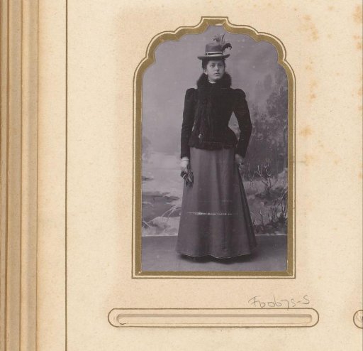 Portrait of a standing woman with a hat, against a backdrop