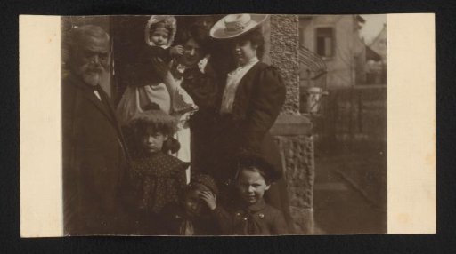 Group portrait of two women and four children in front of a house