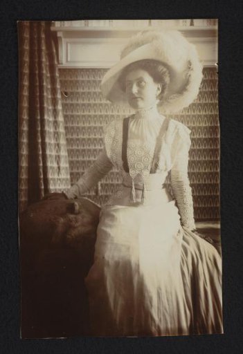 Portrait of a seated woman in interior, with hat and lace blouse