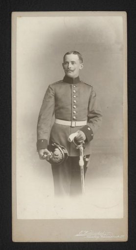 Portrait of a standing man in military uniform with sabre and helmet