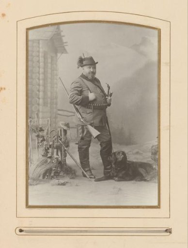 Portrait of a man in uniform with a hunting rifle and a dog at his feet
