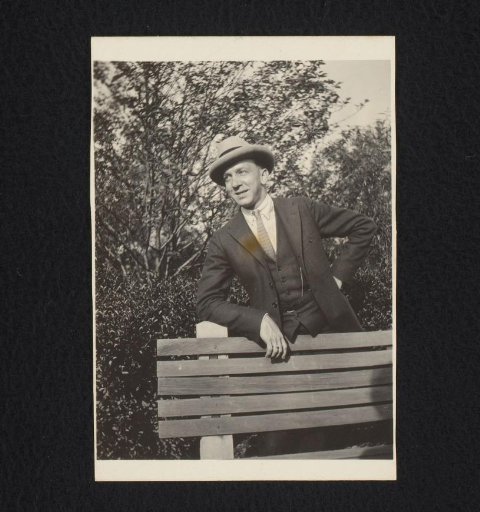 Portrait of a man with a hat, leaning on a bench in a park