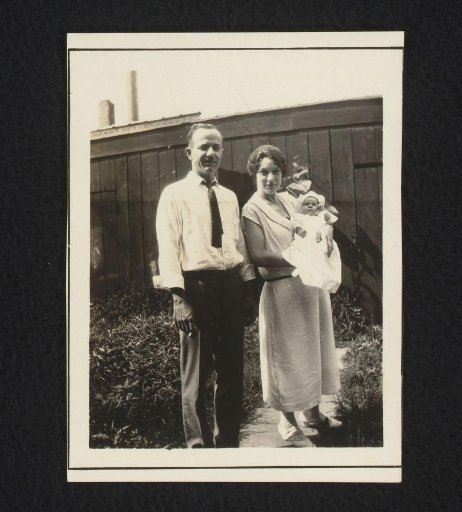 Portrait of a man and a woman with a baby, standing in a garden