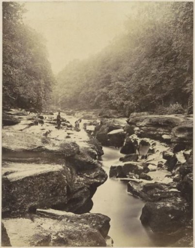 Man standing on boulders along a river in England
