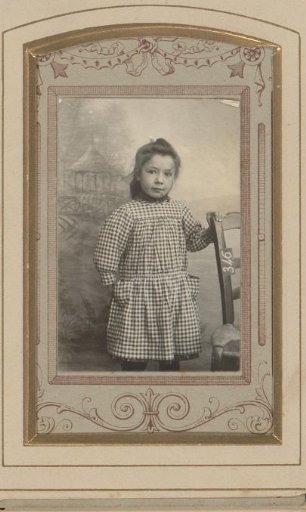 Portrait of a girl standing by a chair