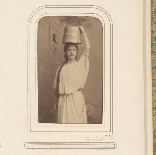 Portrait of a standing actress with a basin on her head, presumably Vendela Andersson-Sörensen
