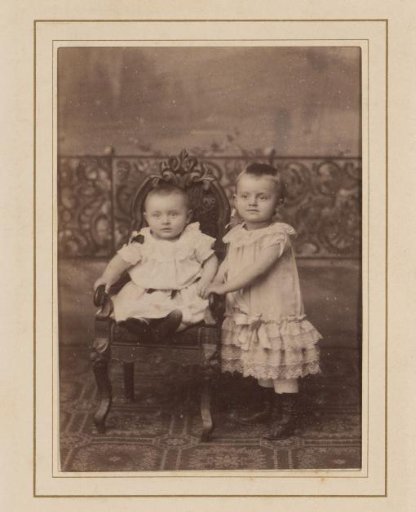 Portrait of Two Toddlers, One Sitting on a Chair