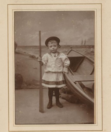 Portrait of a boy holding an oar, next to a rowing boat