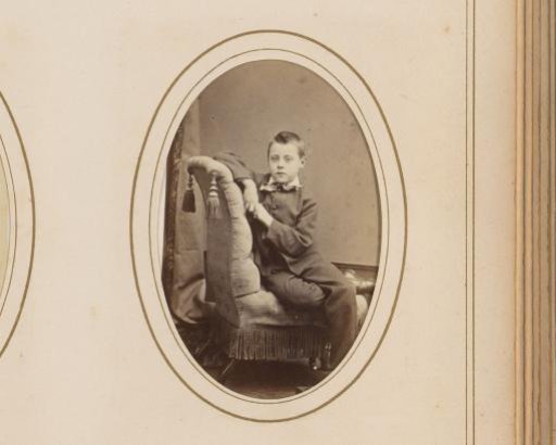 Portrait of a Boy Seated on a Chair with an Album at His Feet