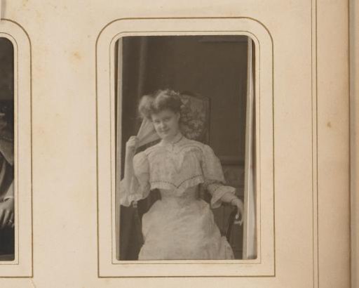 Portrait of a young woman with a fan in her hand, seated on a chair