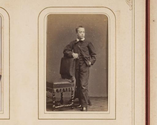 Portrait of a boy standing by a chair