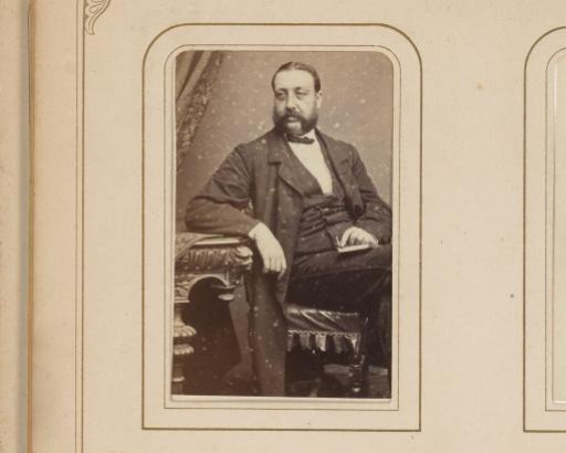 Portrait of a man seated on a chair with a book on his lap