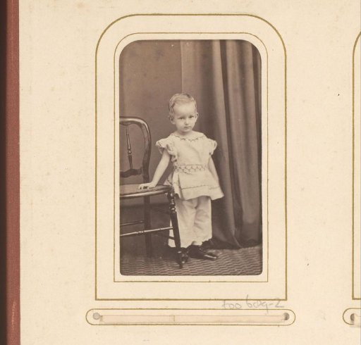 Portrait of a standing boy in breeches suit by a chair