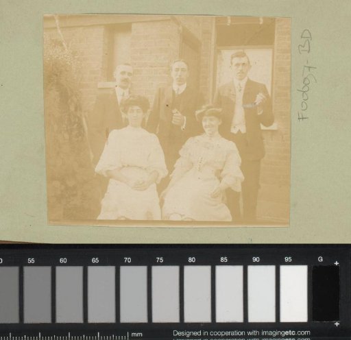 Group portrait of men and women in front of a house
