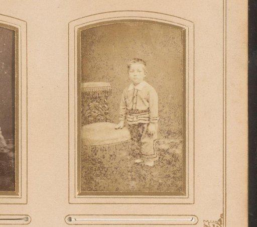 Portrait of a boy, standing by a chair