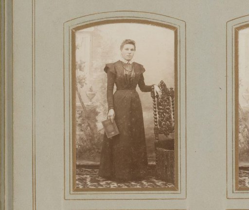 Portrait of a woman holding a book, standing by a chair