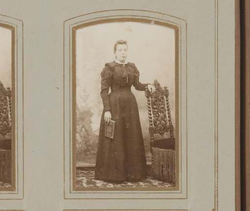 Portrait of a woman holding a book, standing by a chair