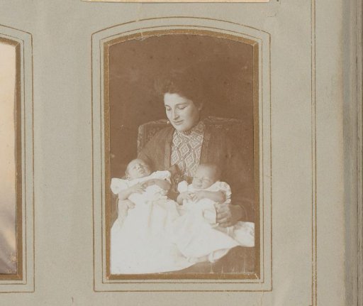 Portrait of a seated woman with two babies on her lap
