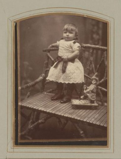 Portrait of a girl standing on a bench with a piece of toy, designated as Annie