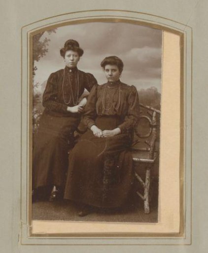 Portrait of two women, seated on a bench of twigs