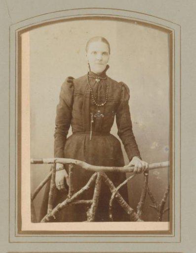 Portrait of a woman standing behind a fence of twigs