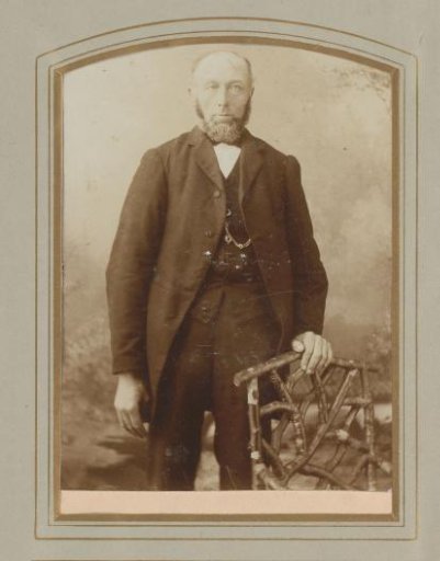 Portrait of a bearded man standing by a chair of twigs