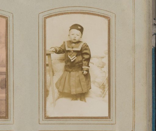 Portrait of a Child with a Headgear, Standing by a Stool