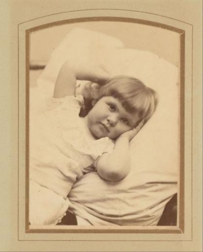 Portrait of a girl in a white dress, lying on a cushion