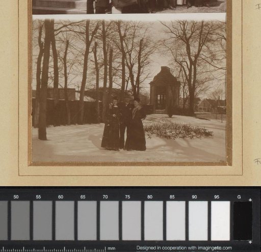 Man and two women standing in the snow by a pavilion