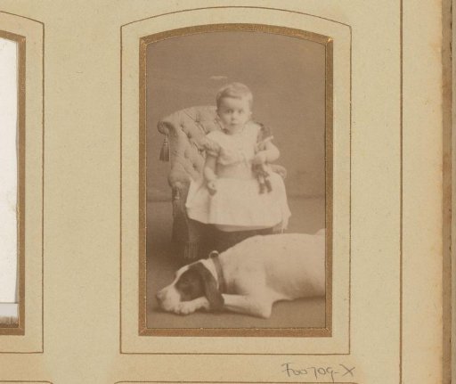 Portrait of a child with a doll, seated on a chair beside a lying dog