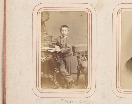Portrait of a boy, standing by a desk with a book